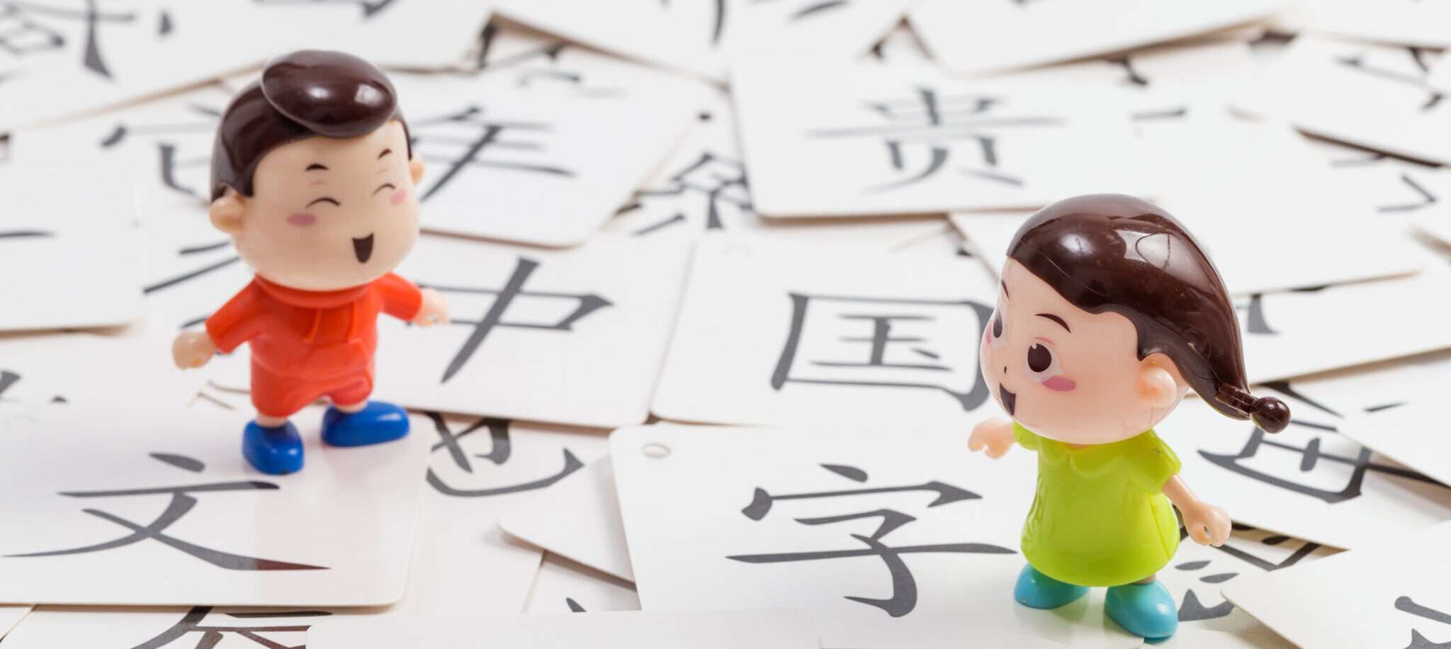 中国の文字の前に 2 つのおもちゃの人形が立っています。