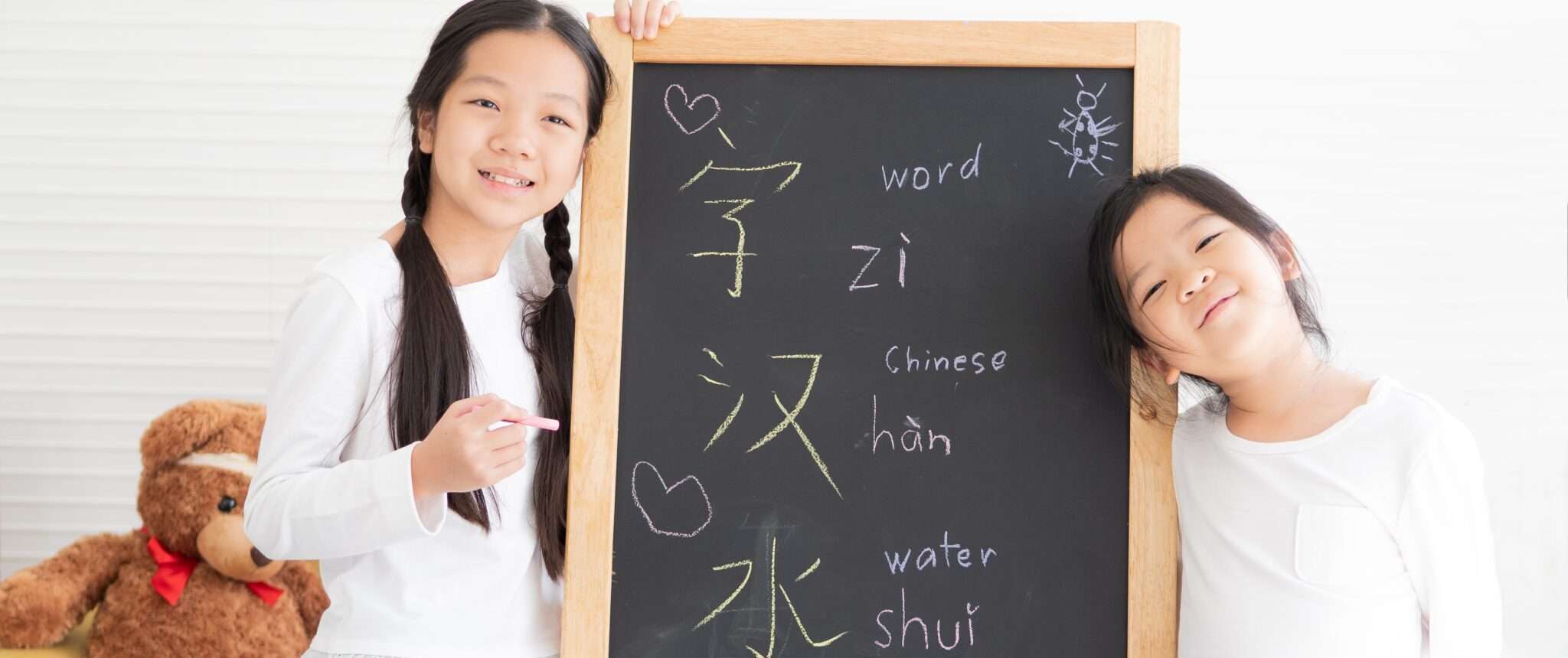 中国語が書かれた黒板を持つ 2 人の女の子。