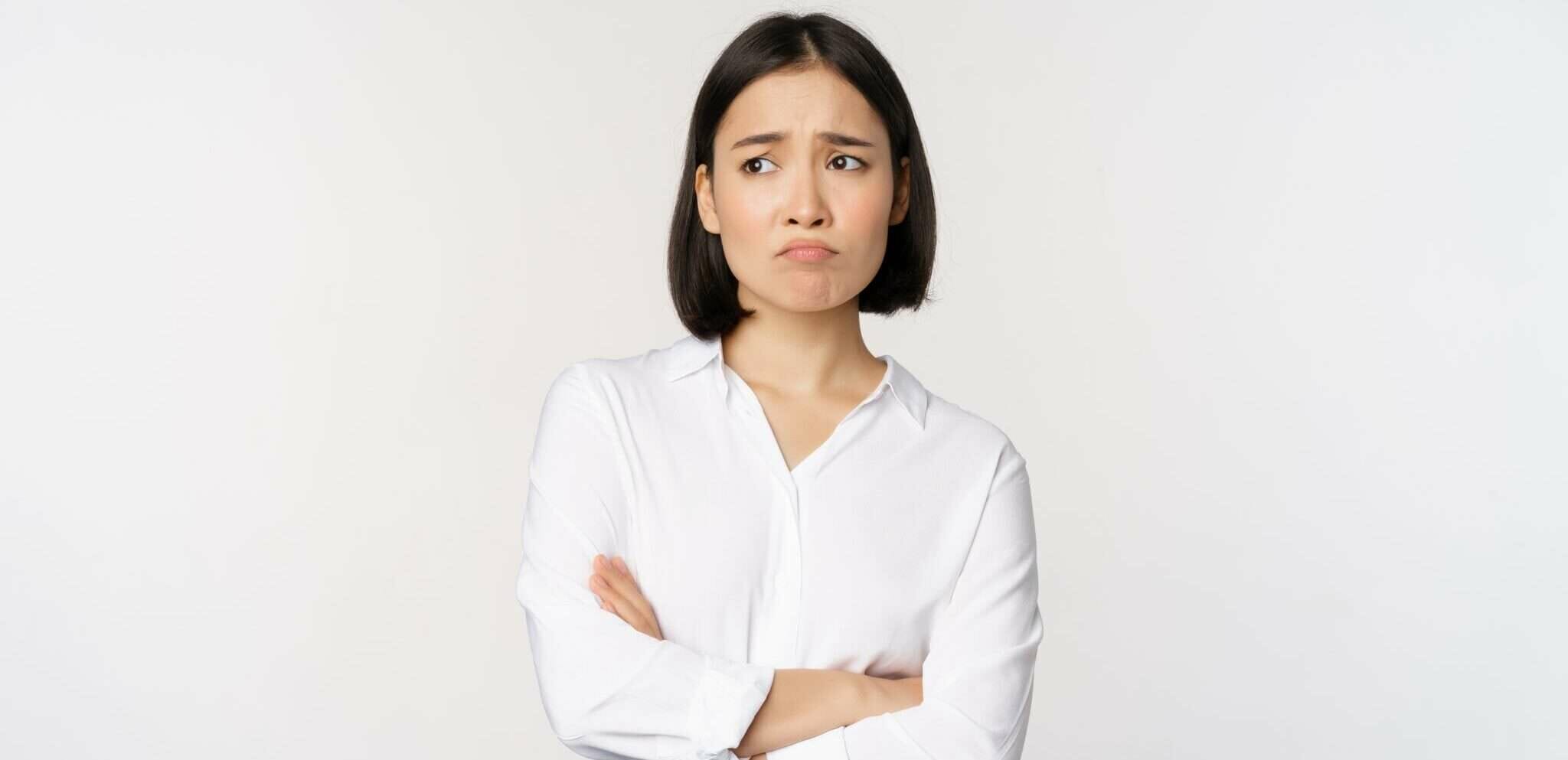 中国の白い背景の前で腕を組む若い女性。