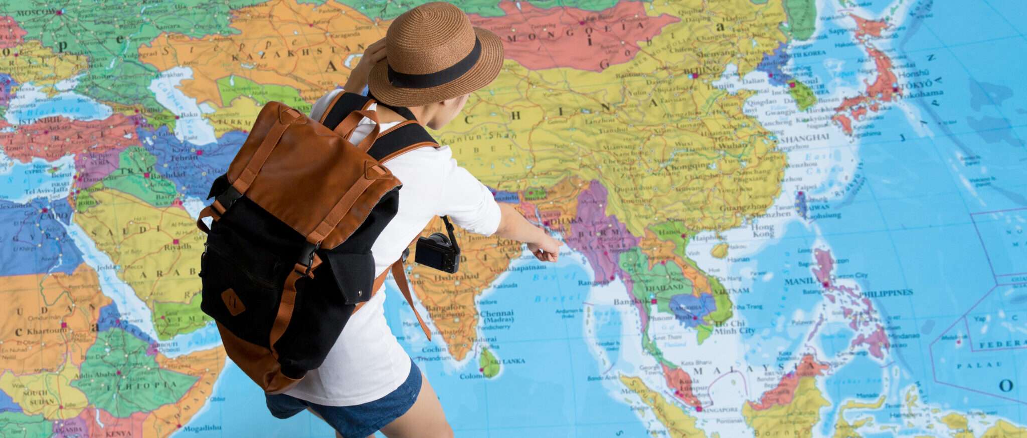 バックパックを背負って世界地図上の中国を探索する女性。