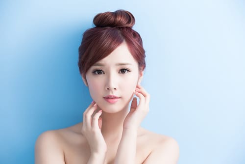 優雅さと優雅さを醸し出し、顔に手を添えたポーズを披露する見事なアジア人女性。 優雅さと優雅さを醸し出し、顔に手を添えたポーズを披露する見事なアジア人女性。