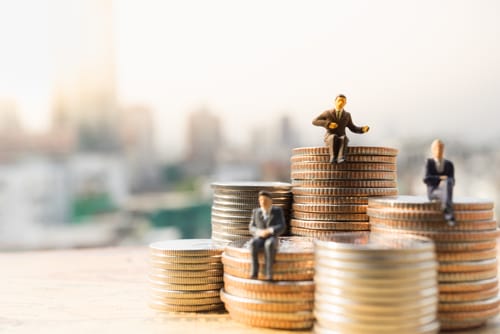 中国のコインの山の上に座るミニチュアのビジネスマン。 中国のコインの山の上に座るミニチュアのビジネスマン。