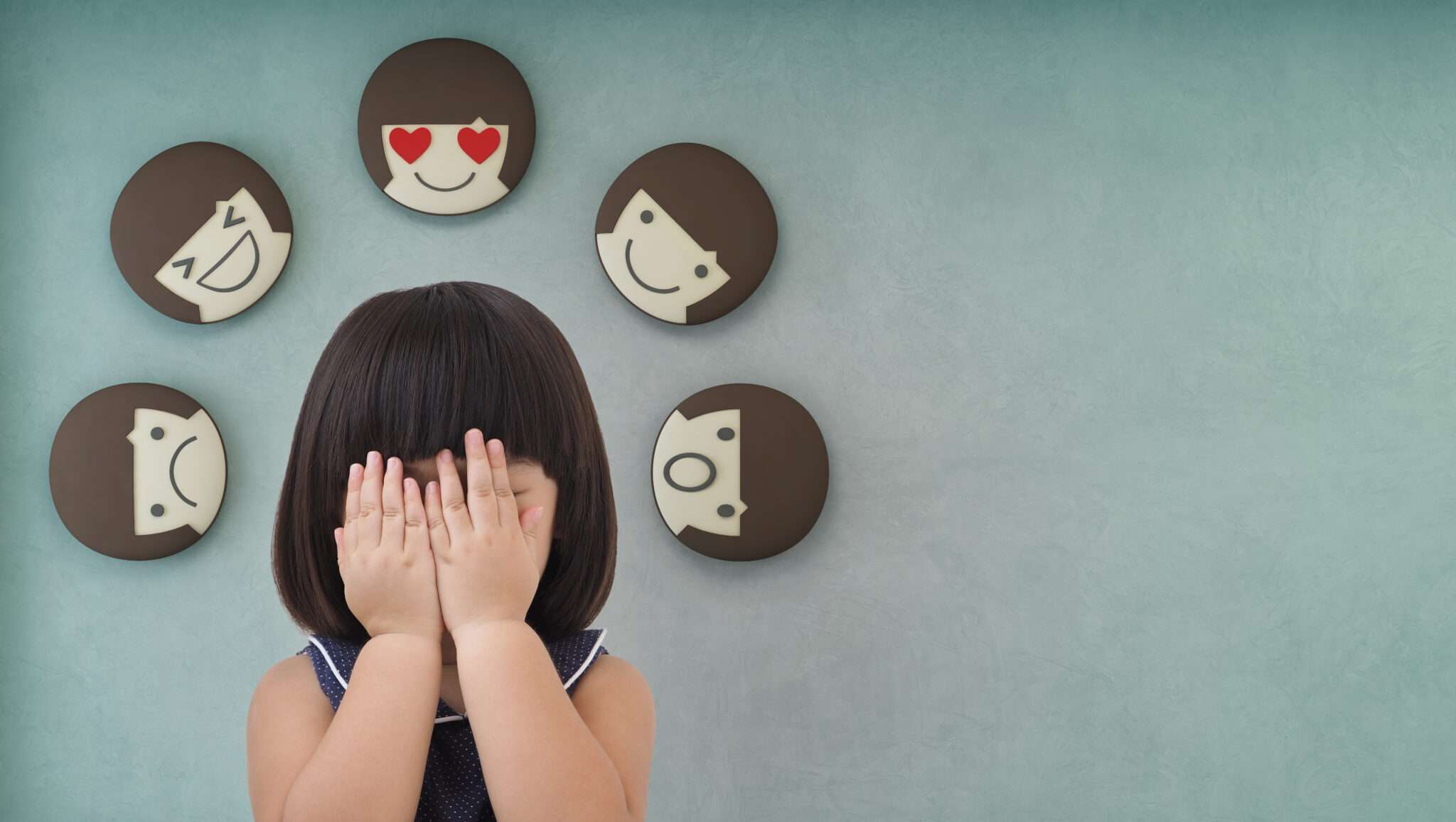 壁にある伝統的な中国のマスクの後ろに隠れている小さな女の子。