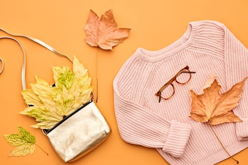 中国の影響を特徴とするオレンジ色の背景にセーター、バッグ、紅葉。 中国の影響を特徴とするオレンジ色の背景にセーター、バッグ、紅葉。