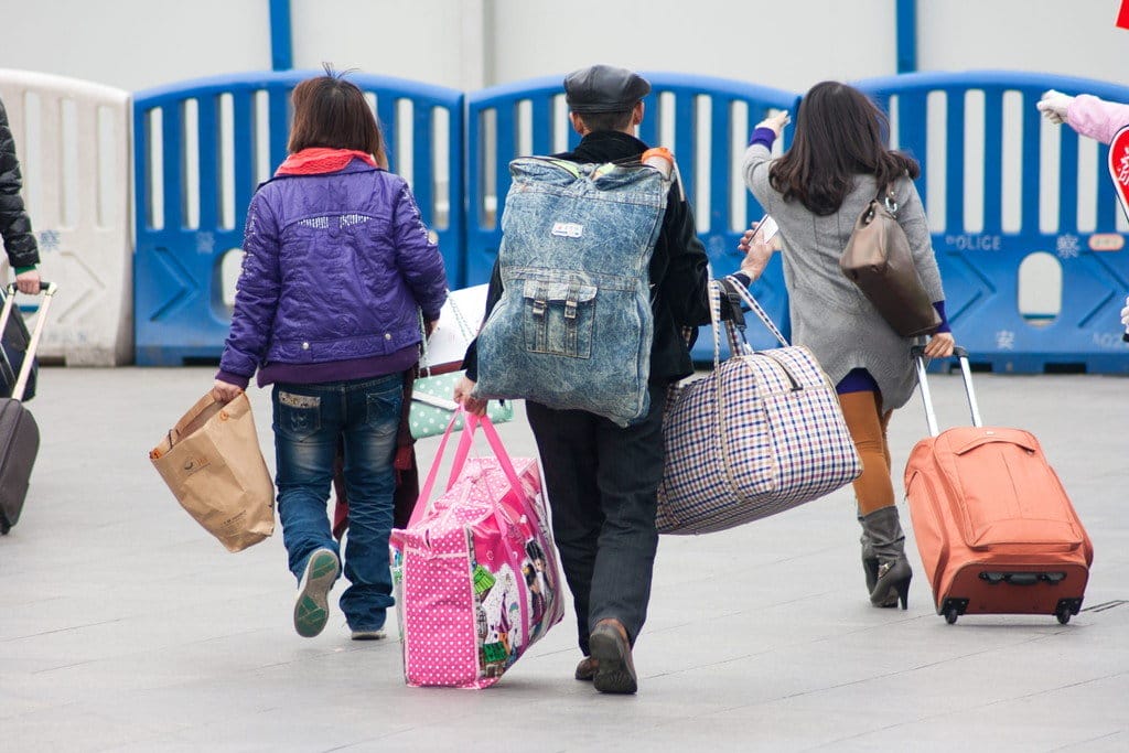 荷物を持って歩く人々のグループ。