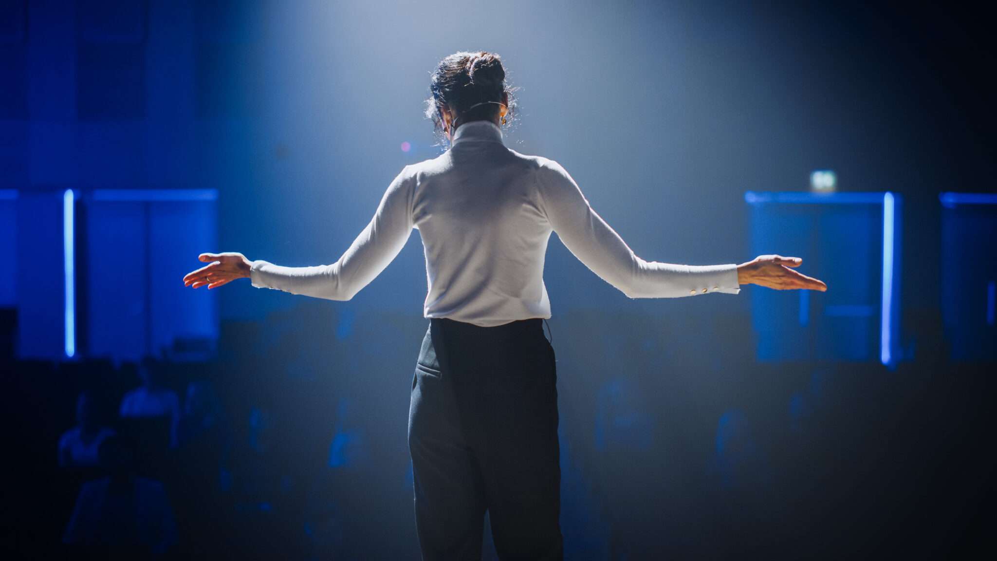 中国のステージに腕を広げて立つ女性。