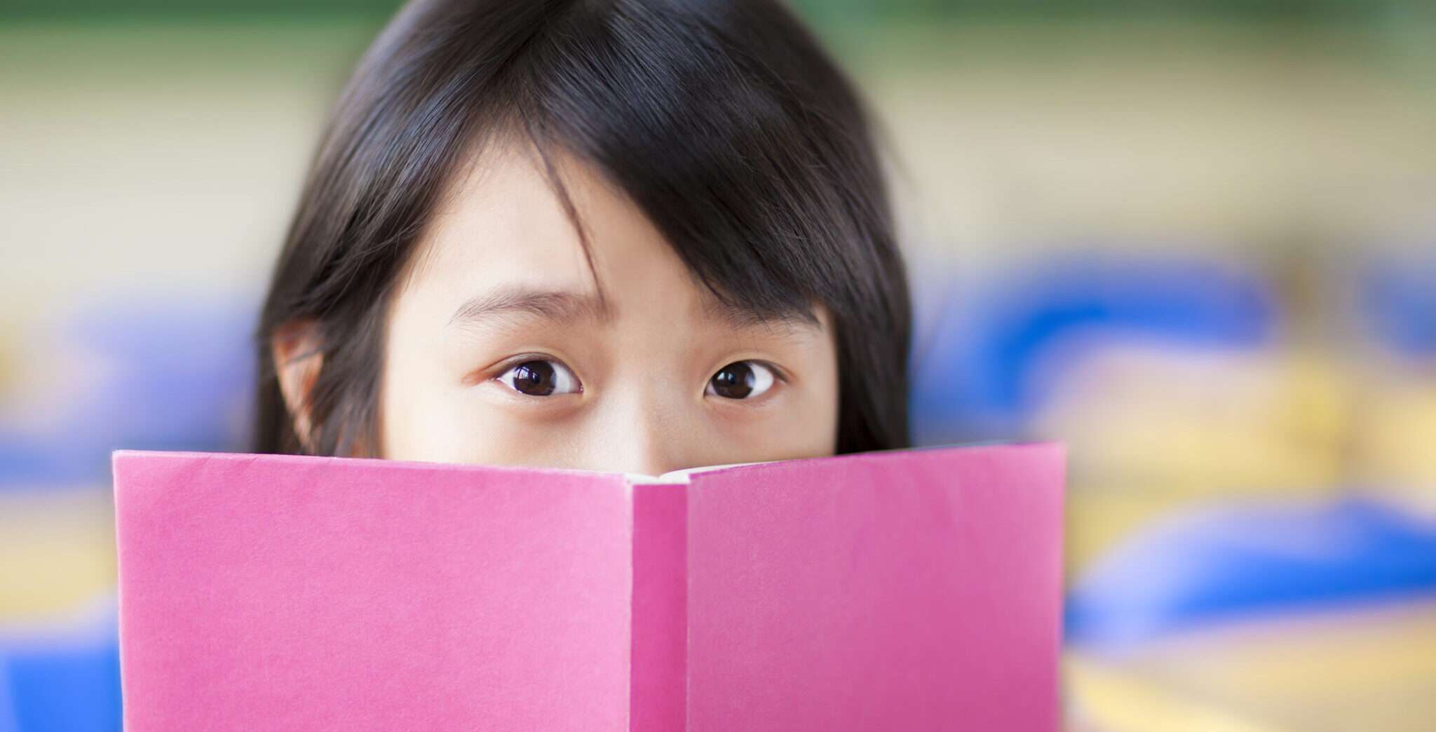 中国語の教室でピンクの本を読んでいる女の子。