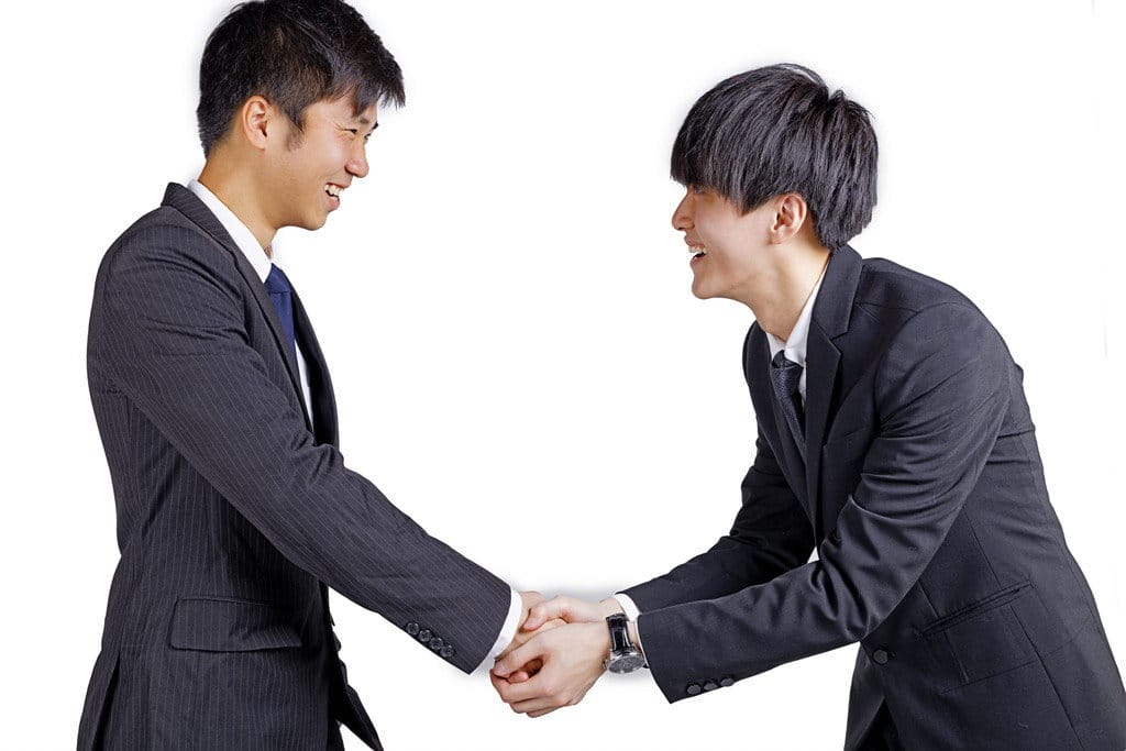 白い背景の前で握手をする 2 人のビジネスマン。