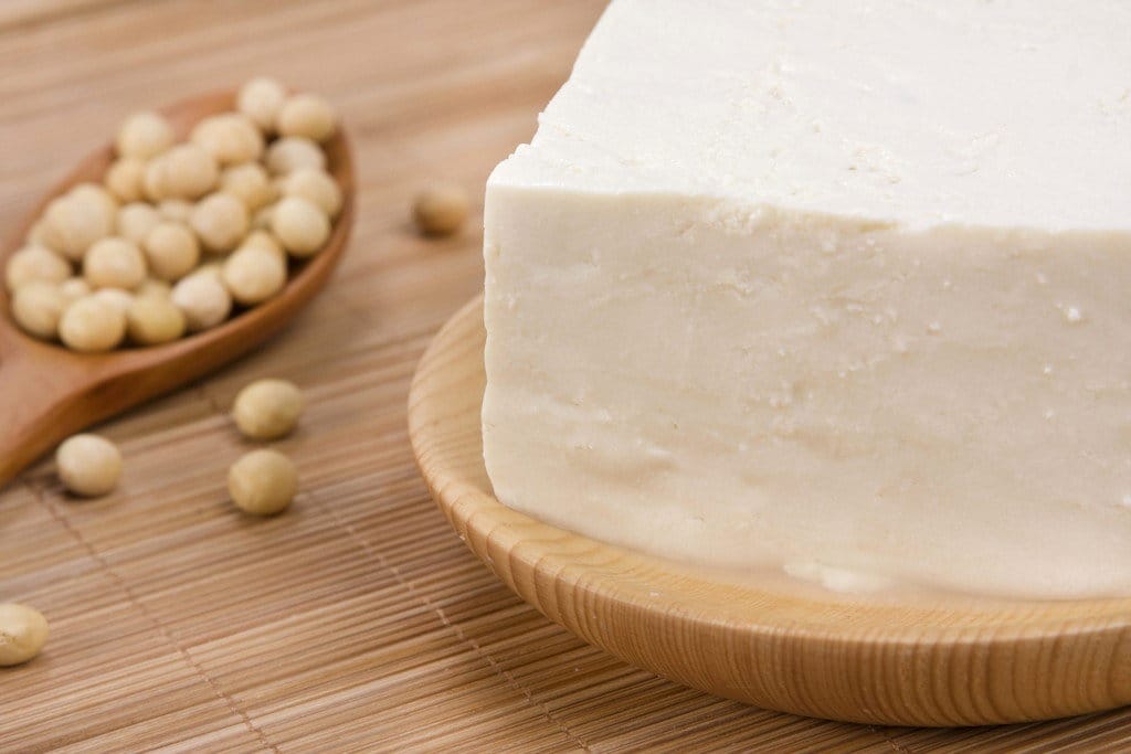 中国の大豆の隣に木の板に置かれた豆腐のブロック。