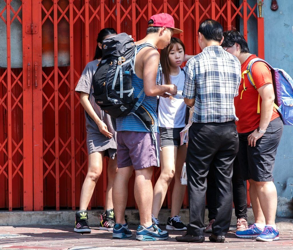 中国の赤い門の前に立つ人々のグループ。 中国の赤い門の前に立つ人々のグループ。