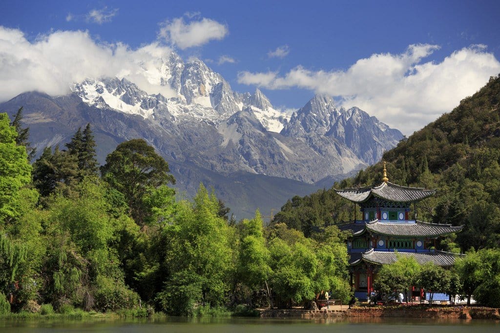 中国の美しい風景を切り取ったかのような雄大な山々に囲まれた、静かな湖の前に建つ塔。