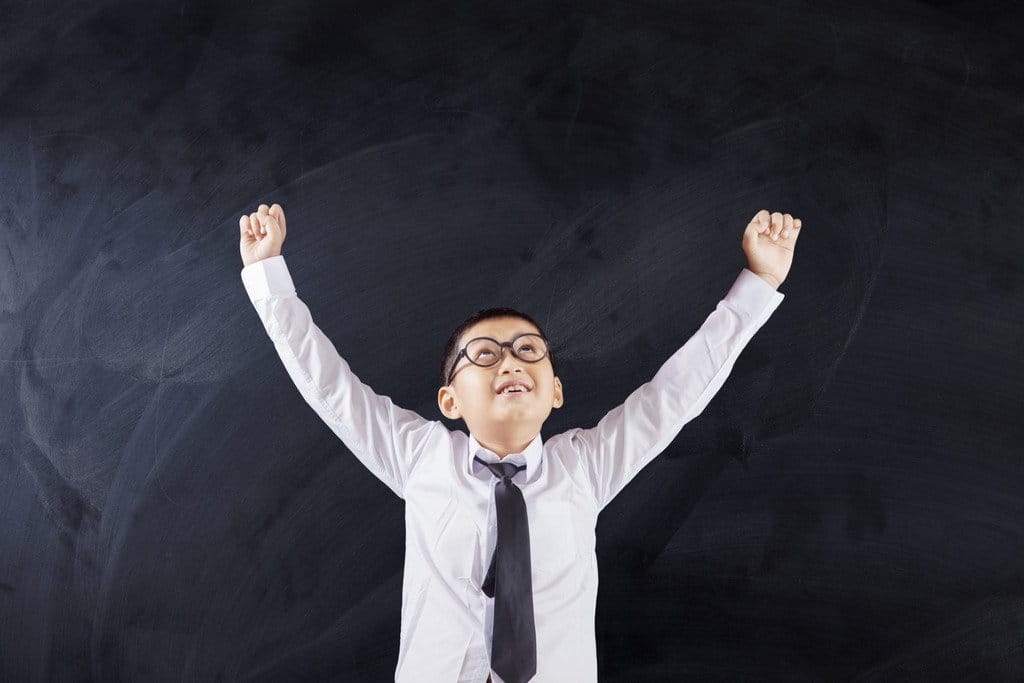 中国の黒板の前で腕を高く上げている少年。