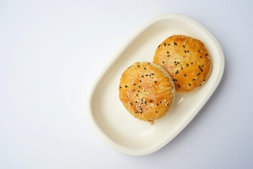 中国の白い皿にゴマ饅頭が 2 つ。