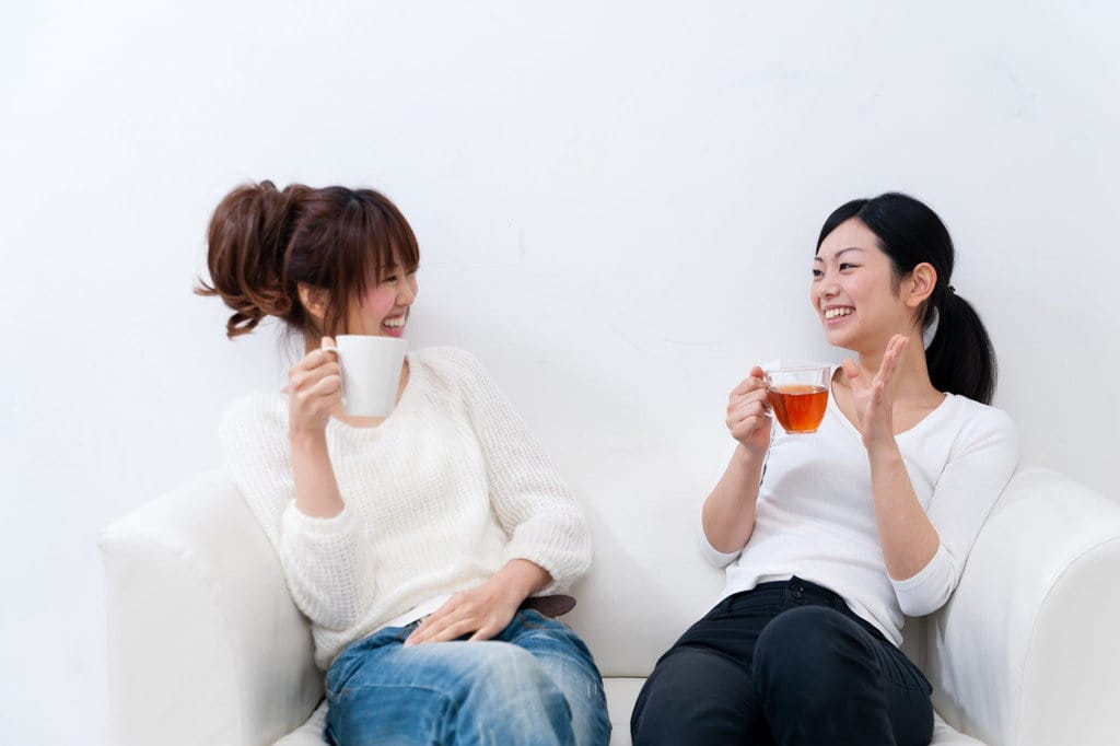 中国の 2 人の女性が白いソファに座ってお茶を飲んでいます。