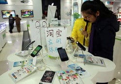 中国の店舗で携帯電話を見ている人々のグループ。 中国の店舗で携帯電話を見ている人々のグループ。
