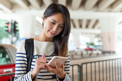 中国の路上で若い女性が携帯電話を使用しています。