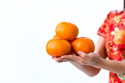 中国から来た女性が手にオレンジの束を持っています。 中国から来た女性が手にオレンジの束を持っています。