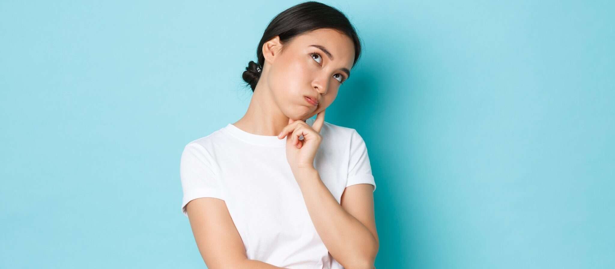 中国出身の白いTシャツを着て顎に手を当てている女性。