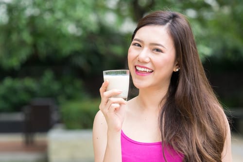 牛乳を一杯飲む中国の若い女性。