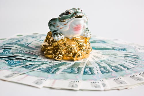 お金の山の上に座っている中国のカエル。