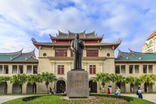 中国の建物の前にある男性の銅像。