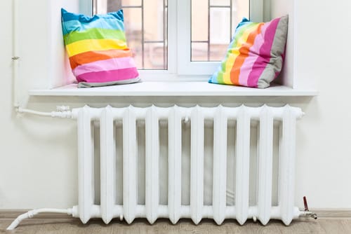 中国の窓の前にカラフルな枕が置かれた白いラジエーター。 中国の窓の前にカラフルな枕が置かれた白いラジエーター。