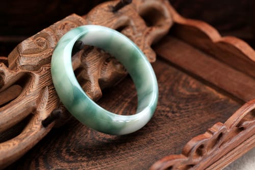 中国産の緑色の翡翠のバングルが木製のテーブルの上に置かれています。