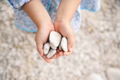 中国で一握りの小石を手に持つ少女。