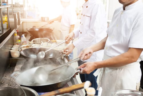 業務用厨房で料理を準備する中国からのシェフのグループ。