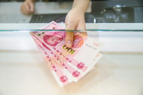 カウンターの前で手には中国の通貨の束が握られています。 カウンターの前で手には中国の通貨の束が握られています。
