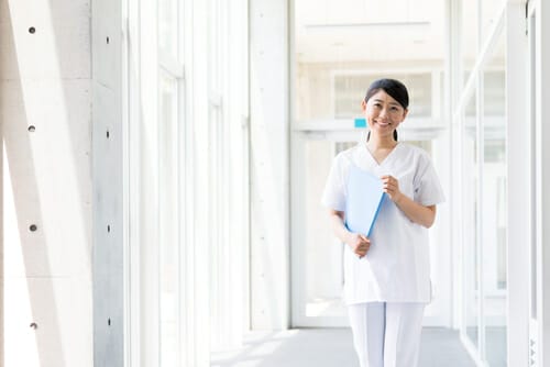 廊下でフォルダーを持っている中国人の女性看護師。