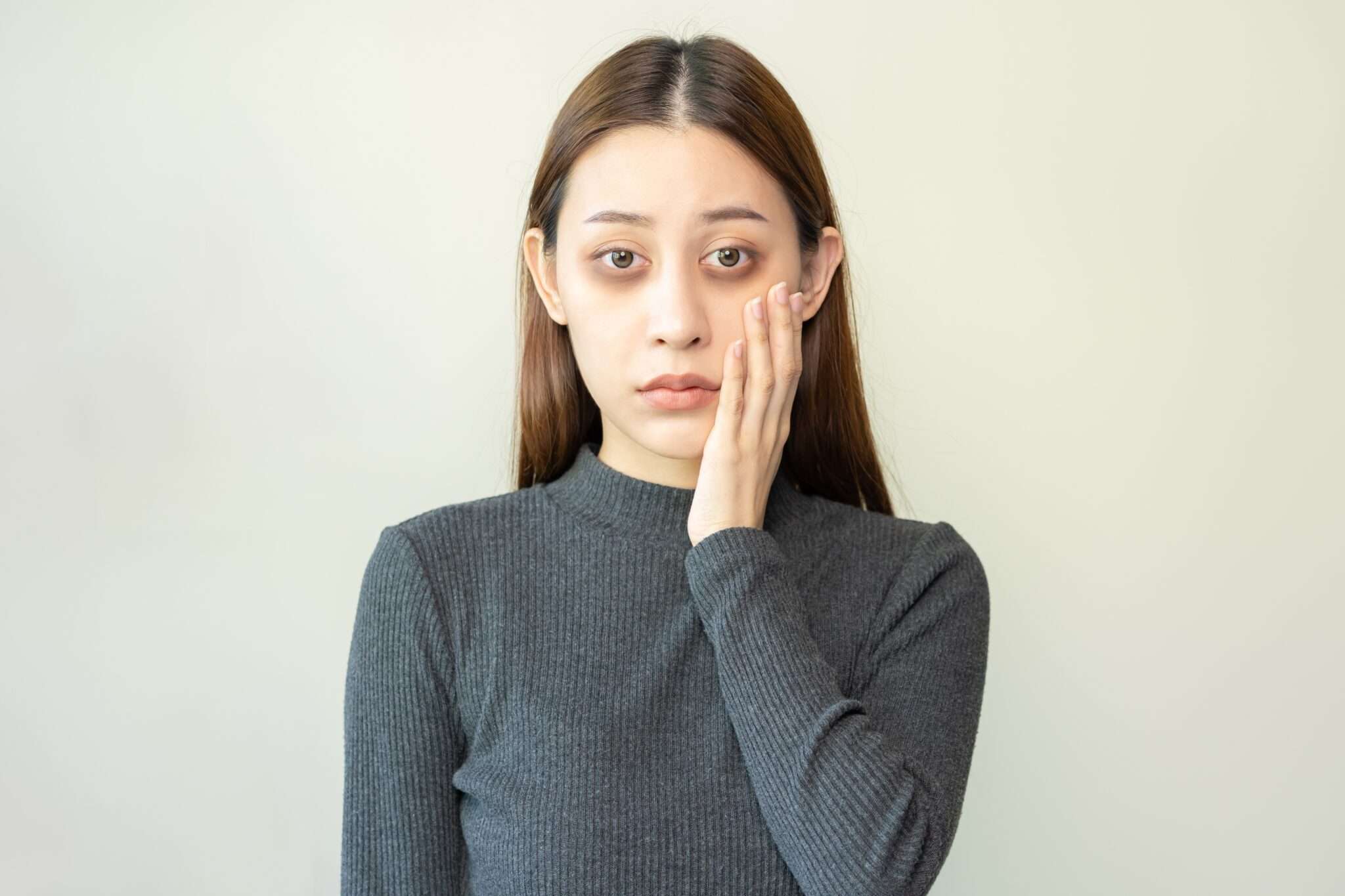 顔に手を当てた中国出身の若いアジア人女性。 顔に手を当てた中国出身の若いアジア人女性。