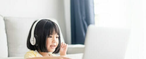 中国の若い女の子が音楽を聴きながらラップトップを使用しています。