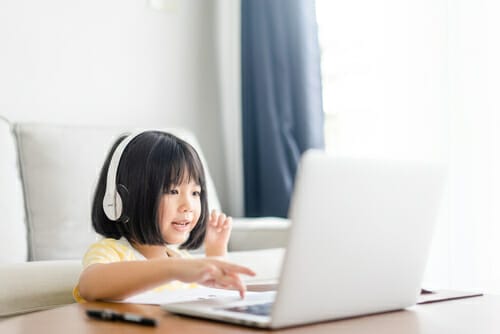 中国の若い女の子が音楽を聴きながらラップトップを使用しています。