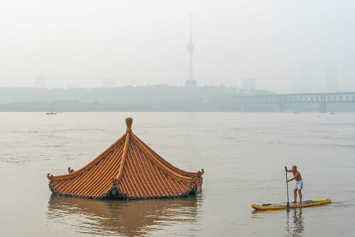 中国の霞んだ川でカヌーを漕ぐ男性。