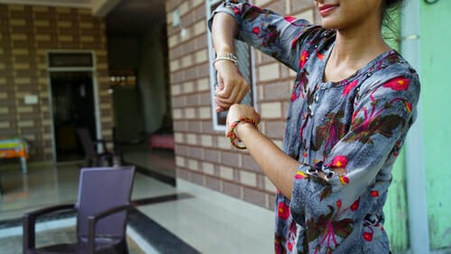 中国出身の女性が家の前で手首を調整している。