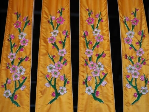 中国の伝統的なデザインからインスピレーションを得た、花が描かれた 3 つの黄色のシルク カーテン。