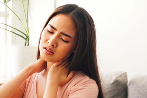 中国から来た女性が首に手を当ててソファに座っています。