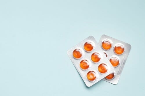 中国の青い背景にオレンジ色の錠剤のパック。 中国の青い背景にオレンジ色の錠剤のパック。