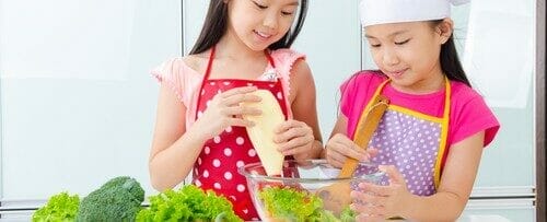 2 人の若い女の子が中国のキッチンで野菜を準備しています。