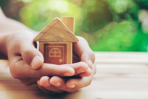 中国 家の木製模型を持つ人の手。 中国 家の木製模型を持つ人の手。