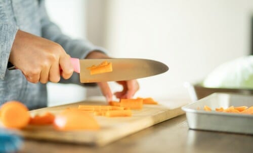 中国で子供がまな板の上でニンジンを切っている。 中国で子供がまな板の上でニンジンを切っている。