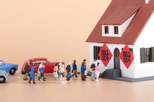 中国の家と車の前に立つ人々のグループ。