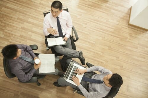 中国のオフィスでノートパソコンを持って座っているビジネスマンのグループ。 中国のオフィスでノートパソコンを持って座っているビジネスマンのグループ。