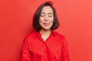 赤い背景に目を閉じたアジア系の若い女性が中国の美しさを表現しています。 赤い背景に目を閉じたアジア系の若い女性が中国の美しさを表現しています。