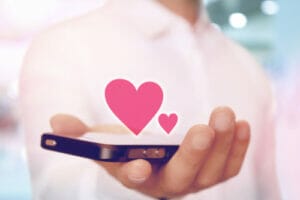 一人の男性が携帯電話の一部を握っており、その上には心形の絵が描かれています。