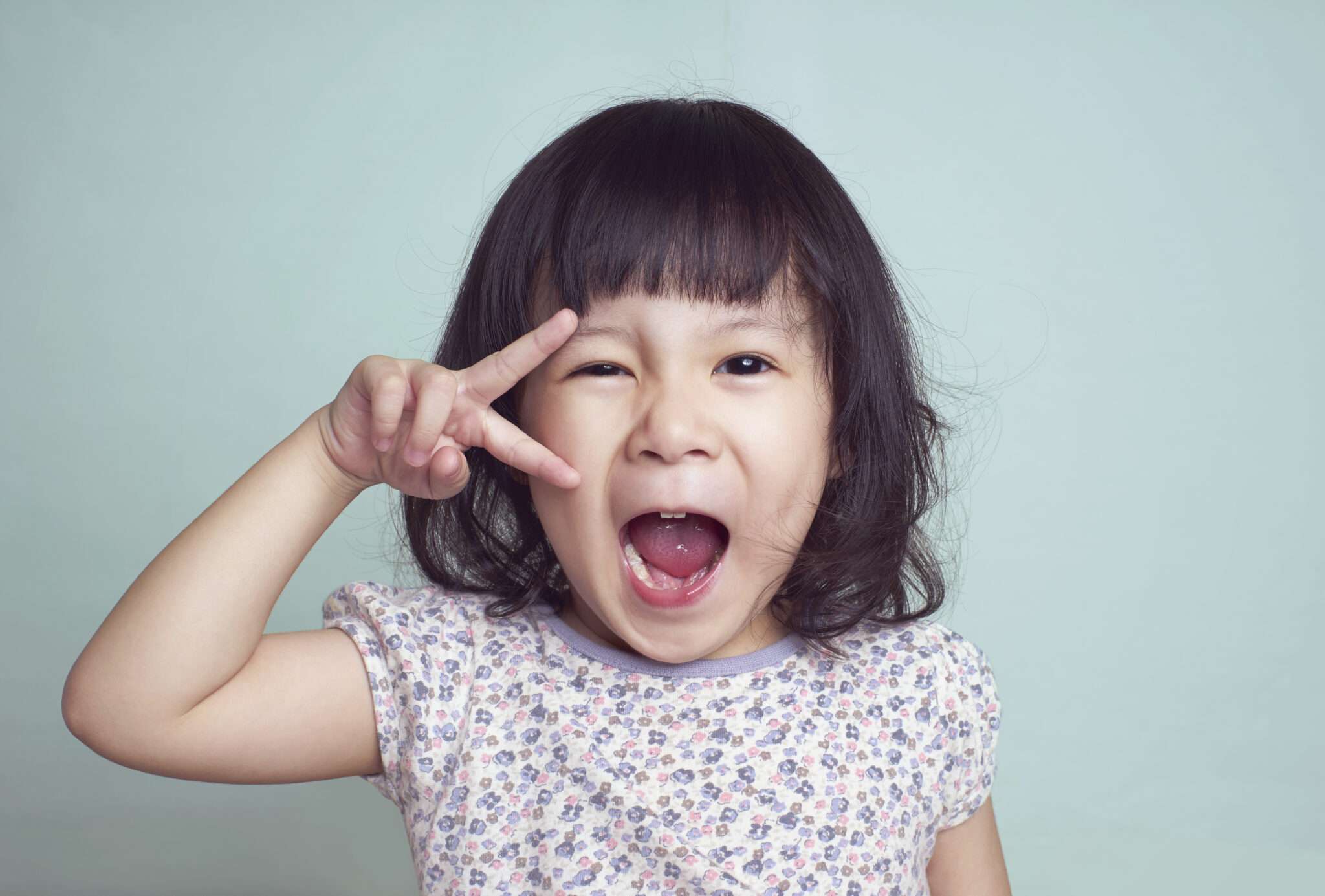 指でサインをする中国の若い女の子。