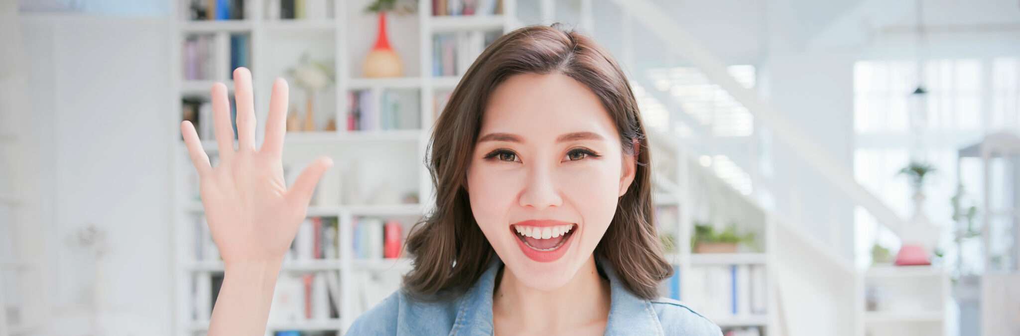 中国の本棚の前で女性が手を振っている。