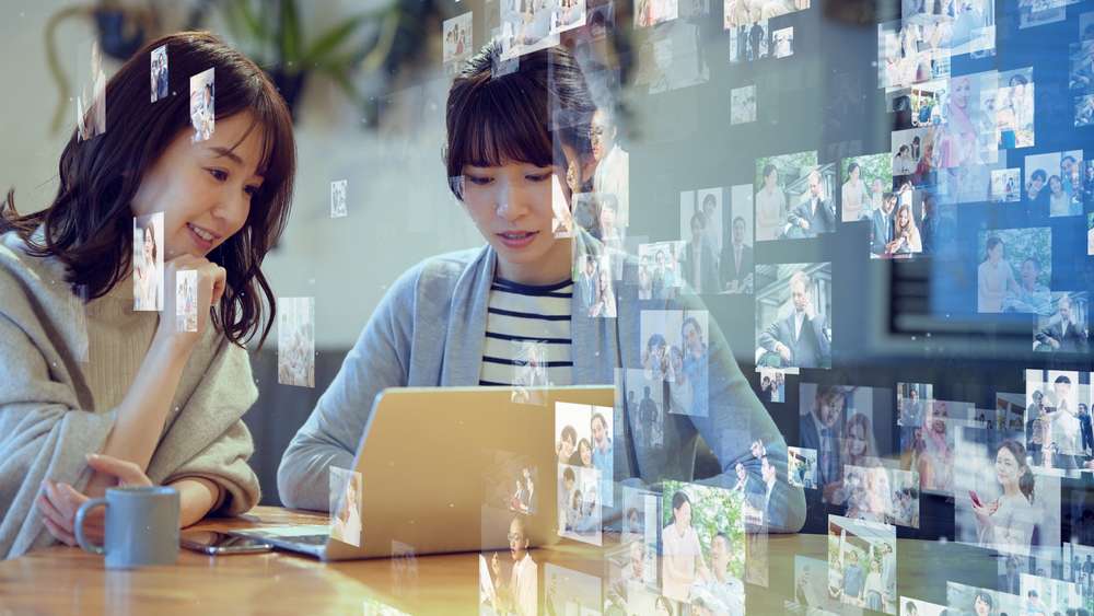 中国でテーブルに座ってラップトップで写真を見ている 2 人の女性。 中国でテーブルに座ってラップトップで写真を見ている 2 人の女性。