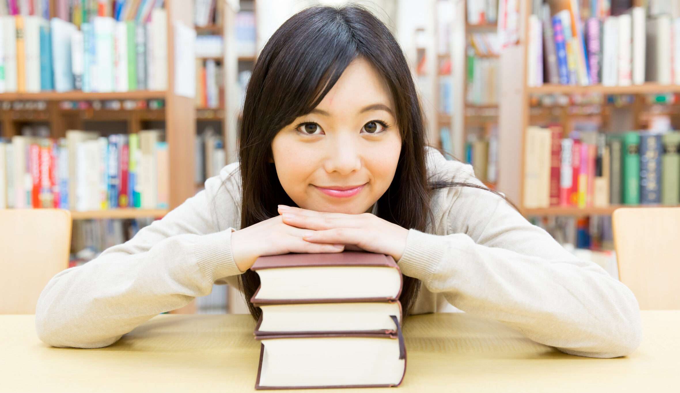 中国の図書館で本の山に寄りかかる女の子。